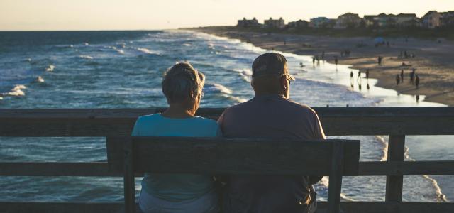 man and woman sitting on bench in front of beach by James Hose Jr courtesy of Unsplash.