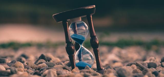 selective focus photo of brown and blue hourglass on stones by Aron Visuals courtesy of Unsplash.