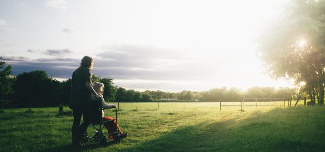 woman standing next to woman riding wheelchair by Dominik Lange courtesy of Unsplash.